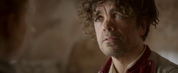 Movie still from “Cyrano” (2021), directed by Joe Wright – A person with curly hair looking at the camera; Close Up shot, Low angle