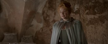 Movie still from “Cyrano” (2021), directed by Joe Wright – A woman with red curly hair wearing a gray cape; Medium shot, Over the shoulder angle