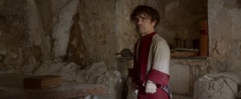 Movie still from “Cyrano” (2021), directed by Joe Wright – A man standing in front of a pile of bags; Medium shot, Low angle