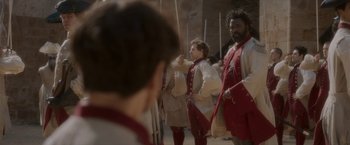 Movie still from “Cyrano” (2021), directed by Joe Wright – A group of people dressed in medieval clothing; Medium shot, Over the shoulder angle