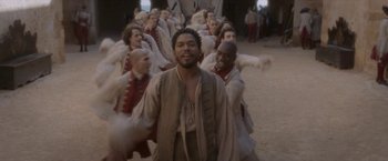 Movie still from “Cyrano” (2021), directed by Joe Wright – A group of men in medieval garb marching in formation; Wide shot, High angle