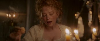 Movie still from “Cyrano” (2021), directed by Joe Wright – A woman with curly red hair is looking at a candle; Close Up shot, High angle