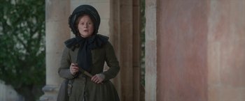 Movie still from “Cyrano” (2021), directed by Joe Wright – A woman dressed in period clothing holding a wooden stick; Medium shot, Low angle