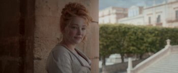Movie still from “Cyrano” (2021), directed by Joe Wright – A beautiful young woman with red hair standing in front of a building; Close Up shot, Over the shoulder angle