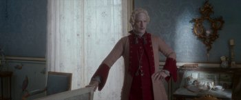 Movie still from “Cyrano” (2021), directed by Joe Wright – A man dressed in period clothing standing in front of a window; Medium shot, Low angle