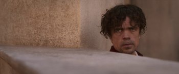 Movie still from “Cyrano” (2021), directed by Joe Wright – A person with curly hair looking at the camera; Medium shot, Low angle