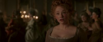 Movie still from “Cyrano” (2021), directed by Joe Wright – A beautiful young woman with curly red hair and green eyes; Close Up shot, Over the shoulder angle