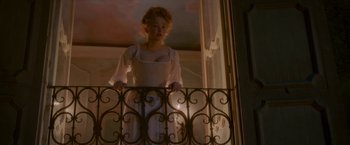 Movie still from “Cyrano” (2021), directed by Joe Wright – A woman standing on a balcony looking out of a window; Wide shot, Low angle