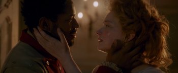 Movie still from “Cyrano” (2021), directed by Joe Wright – A man and a woman face to face in front of lights; Close Up shot, Over the shoulder angle