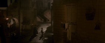 Movie still from “Cyrano” (2021), directed by Joe Wright – Two people walking down a street at night; Extreme Wide shot, High angle