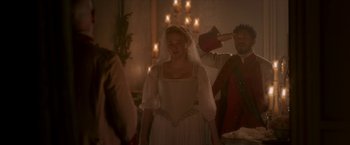 Movie still from “Cyrano” (2021), directed by Joe Wright – A woman in a white dress standing in front of a man; Medium shot, Over the shoulder angle