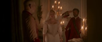 Movie still from “Cyrano” (2021), directed by Joe Wright – A woman in a wedding dress standing in front of two men; Medium shot, Over the shoulder angle