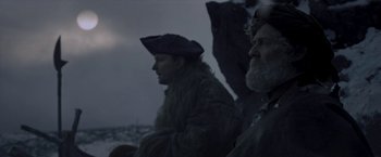 Movie still from “Cyrano” (2021), directed by Joe Wright – Two men are sitting in the snow at night; Medium shot, Low angle