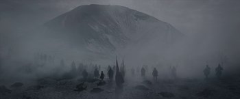 Movie still from “Cyrano” (2021), directed by Joe Wright – A group of people walking through the fog on a mountain; Extreme Wide shot, High angle