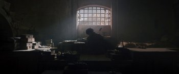 Movie still from “Cyrano” (2021), directed by Joe Wright – A person sitting in a room next to a window; Wide shot, Low angle