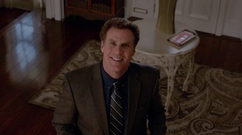Movie still from “Daddy's Home” (2015), directed by Sean Anders – A man wearing a suit and tie sitting in a room; Medium shot, High angle