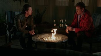 Movie still from “Daddy's Home” (2015), directed by Sean Anders – Two men are sitting around a fire pit; Wide shot, High angle