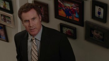 Movie still from “Daddy's Home” (2015), directed by Sean Anders – A man wearing a suit and tie standing in front of a wall; Medium shot, Over the shoulder angle