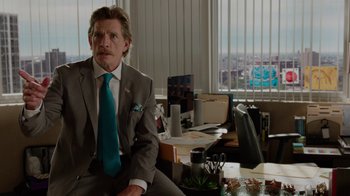 Movie still from “Daddy's Home” (2015), directed by Sean Anders – A man sitting at a desk wearing a suit and tie; Medium shot, Over the shoulder angle