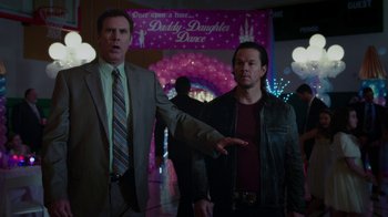 Movie still from “Daddy's Home” (2015), directed by Sean Anders – Two men standing next to each other in front of a party; Medium shot, Over the shoulder angle