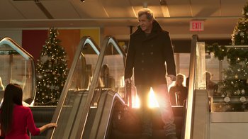 Movie still from “Daddy's Home 2” (2017), directed by Sean Anders – A man in a black coat is going down an escalator; Wide shot, Low angle