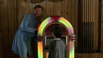 Movie still from “Daddy's Home 2” (2017), directed by Sean Anders – A man and a boy standing in front of a jukebox; Medium shot, Over the shoulder angle