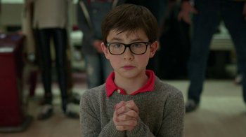 Movie still from “Daddy's Home 2” (2017), directed by Sean Anders – A young boy with glasses is holding his hands in prayer; Medium shot, High angle
