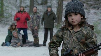 Movie still from “Daddy's Home 2” (2017), directed by Sean Anders – A young girl in a camo jacket and a group of people in the background; Medium shot, Over the shoulder angle