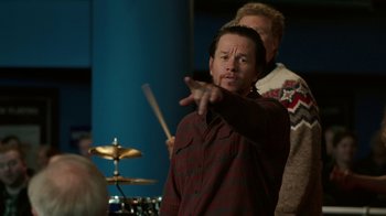 Movie still from “Daddy's Home 2” (2017), directed by Sean Anders – A man in a plaid shirt is playing drums; Medium shot, Over the shoulder angle