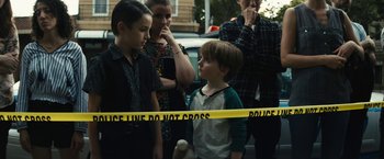 Movie still from “Daniel Isn't Real” (2019), directed by Adam Egypt Mortimer – A group of people standing next to a police line; Medium shot, High angle