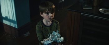 Movie still from “Daniel Isn't Real” (2019), directed by Adam Egypt Mortimer – A young boy sitting at a table holding a bowl of food; Close Up shot, High angle