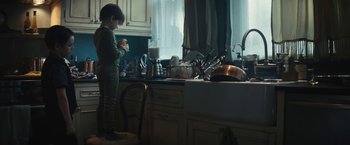 Movie still from “Daniel Isn't Real” (2019), directed by Adam Egypt Mortimer – A young boy standing in a kitchen next to a sink; Medium shot, Low angle
