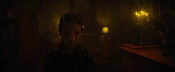 Movie still from “Daniel Isn't Real” (2019), directed by Adam Egypt Mortimer – A young girl is sitting in a dimly - lit room; Medium shot, High angle