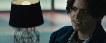 Movie still from “Daniel Isn't Real” (2019), directed by Adam Egypt Mortimer – A man sitting in front of a table with a lamp; Close Up shot, Over the shoulder angle