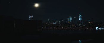 Movie still from “Daniel Isn't Real” (2019), directed by Adam Egypt Mortimer – A view of a city skyline at night with a full moon in the background; Extreme Wide shot, High angle