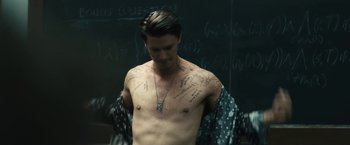 Movie still from “Daniel Isn't Real” (2019), directed by Adam Egypt Mortimer – A shirtless man standing in front of a chalkboard; Medium shot, High angle