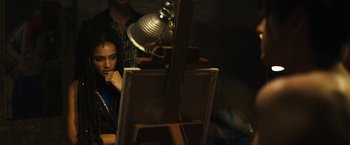 Movie still from “Daniel Isn't Real” (2019), directed by Adam Egypt Mortimer – A man and a woman sitting in front of an easel; Medium shot, High angle