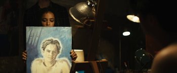 Movie still from “Daniel Isn't Real” (2019), directed by Adam Egypt Mortimer – A person holding a painting in front of an easel; Medium shot, Over the shoulder angle