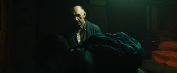 Movie still from “Daniel Isn't Real” (2019), directed by Adam Egypt Mortimer – An older man standing in a dark room; Medium shot, Over the shoulder angle