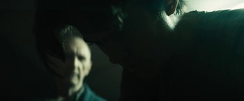 Movie still from “Daniel Isn't Real” (2019), directed by Adam Egypt Mortimer – A man is looking at the camera in a dark room; Close Up shot, Over the shoulder angle