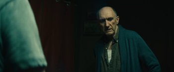 Movie still from “Daniel Isn't Real” (2019), directed by Adam Egypt Mortimer – An older man standing in a dark room; Close Up shot, Low angle