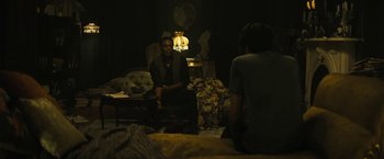 Movie still from “Daniel Isn't Real” (2019), directed by Adam Egypt Mortimer – Two people sitting in a dark room with a lamp; Medium shot, High angle