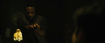 Movie still from “Daniel Isn't Real” (2019), directed by Adam Egypt Mortimer – A man holding a gun in a dark room; Medium shot, Over the shoulder angle