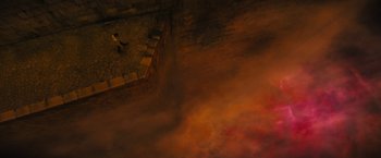 Movie still from “Daniel Isn't Real” (2019), directed by Adam Egypt Mortimer – A person standing on a brick wall near a fire; Extreme Wide shot, Overhead angle