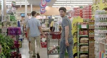 Movie still from “Flower” (2017), directed by Max Winkler – A man pushing a shopping cart in a grocery store; Medium shot, Over the shoulder angle