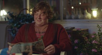 Movie still from “Flower” (2017), directed by Max Winkler – A woman sitting at a table looking at an old photo; Medium shot, Over the shoulder angle