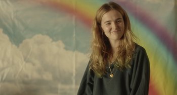 Movie still from “Flower” (2017), directed by Max Winkler – A girl with long blonde hair standing in front of a rainbow; Medium shot, Over the shoulder angle