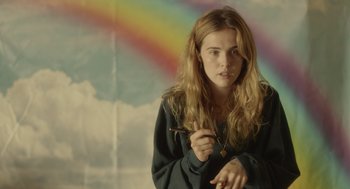 Movie still from “Flower” (2017), directed by Max Winkler – A woman holding a pair of scissors in front of a rainbow; Medium shot, Over the shoulder angle