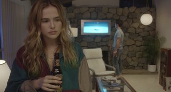 Movie still from “Flower” (2017), directed by Max Winkler – A woman holding a beer in her hand while standing in front of a man; Medium shot, Over the shoulder angle