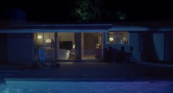 Movie still from “Flower” (2017), directed by Max Winkler – A group of people sitting in front of a house at night; Extreme Wide shot, High angle